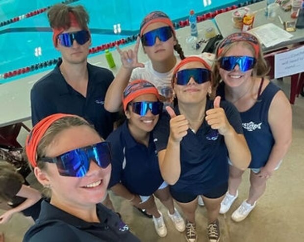 Boundary Bay Bluebacks coaches cheering on deck in team gear and sunglasses